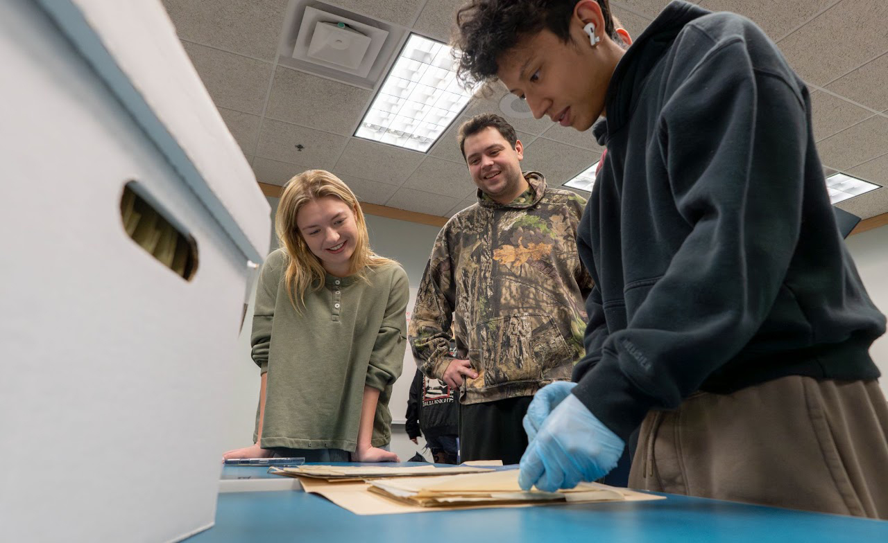 three college students looking at Congdon paper artifacts at the UMD Archives.