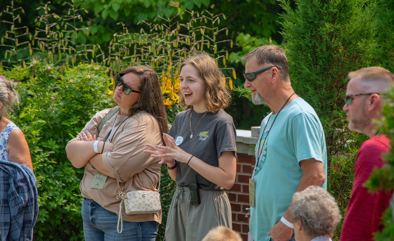 tour guide speaking with a group in the brick exterior formal garden