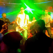 Dead End Friends, three band members playing guitars, bright green stage light behind them.