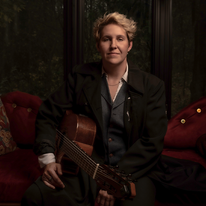 Skarlett Woods sitting and holding a wood guitar, image by Darin Back