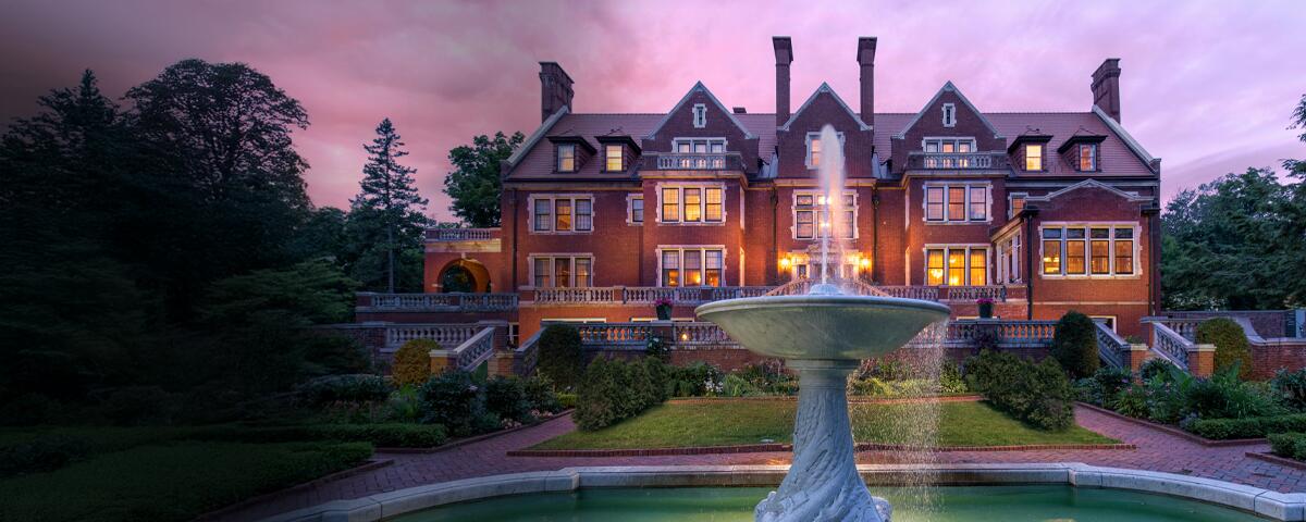 Southside of Glensheen, formal garden, and fountain with a sunset sky