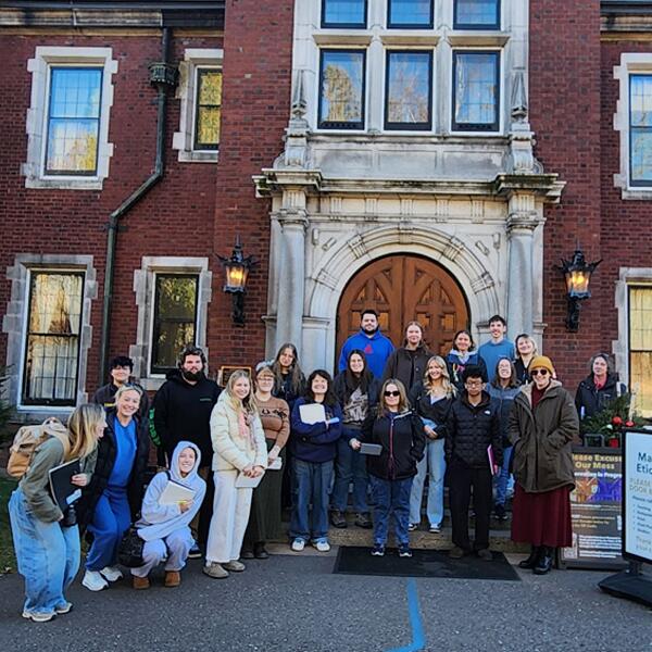 A large group of college students standing in from of the the large doors of Glensheen Mansion.