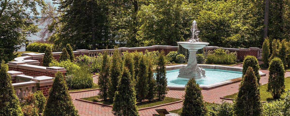 Large water fountain with pruned bushes surrounding.