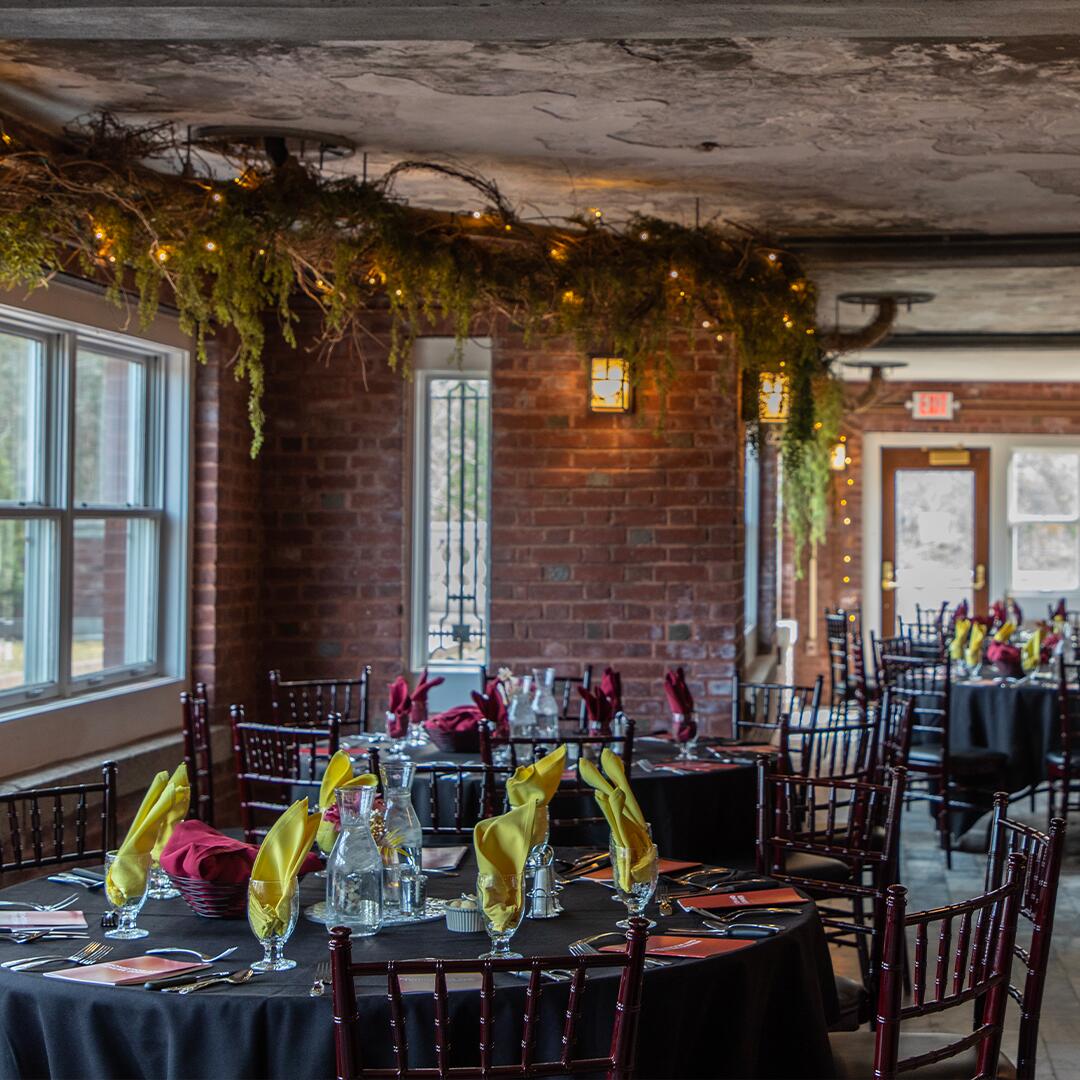 Round tables in brick room, glass cups filled with colored napkins.