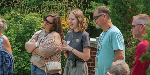 tour guide speaking with a group in the brick exterior formal garden