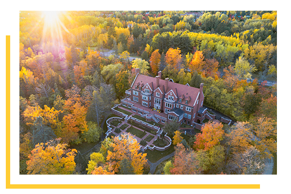 Glensheen shot from above, surrounded by colorful trees in the fall.