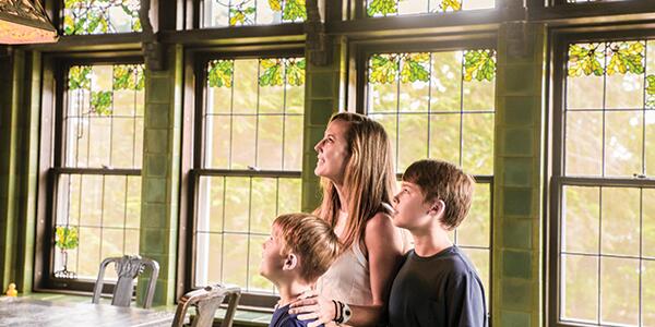 mom and two sons looking at light fixture in the green breakfast room.