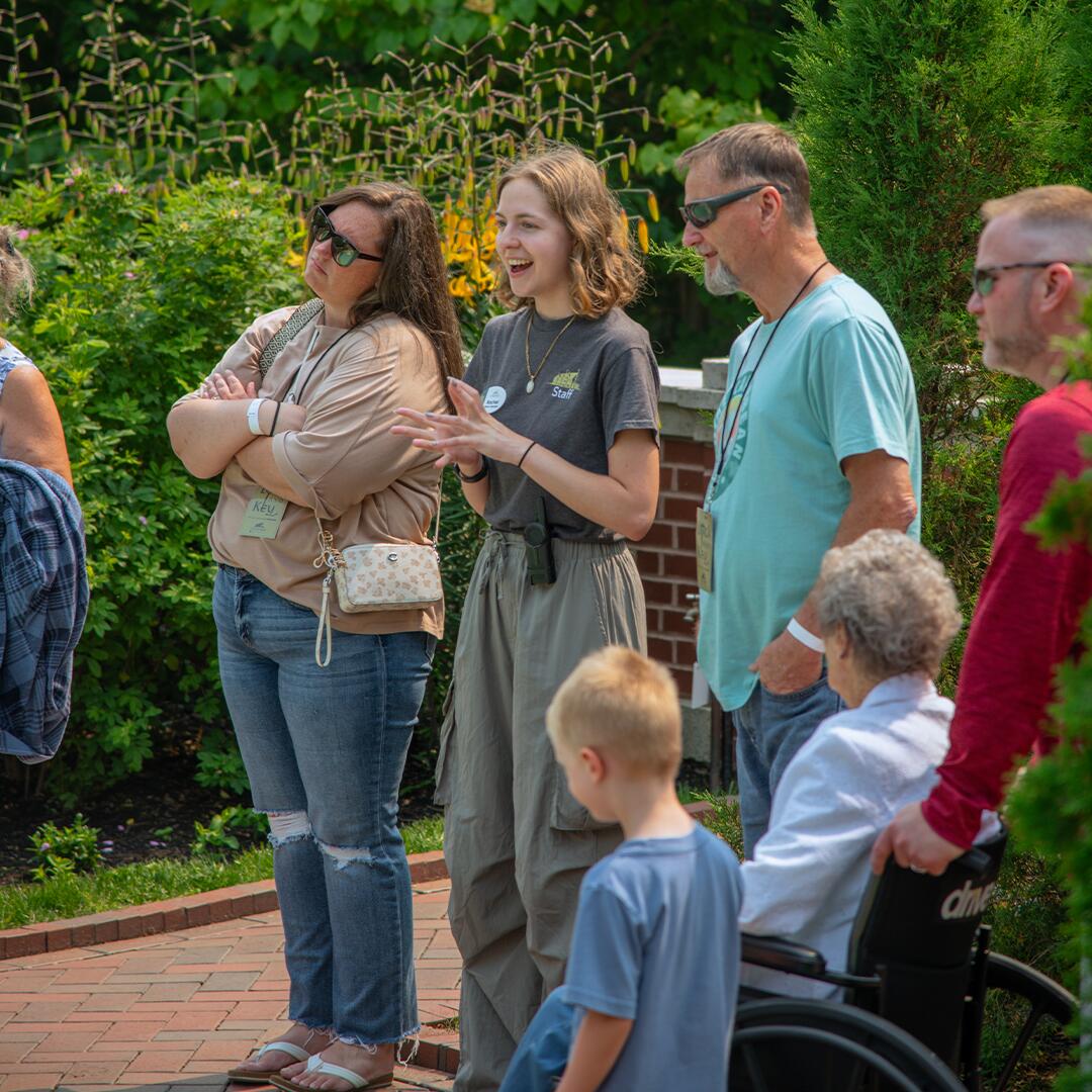 Tour guide speaking with group of guests on brick formal garden.