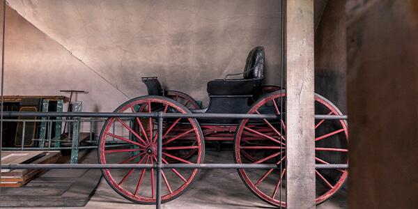 Black carriage with red wood wheels stored in upstairs of the Carriage House.