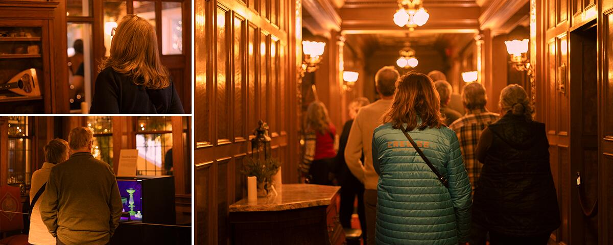large adult group in the wood paneled hall; woman looking at an instrument in a glass case; couple looking at vaseline glass in a case.