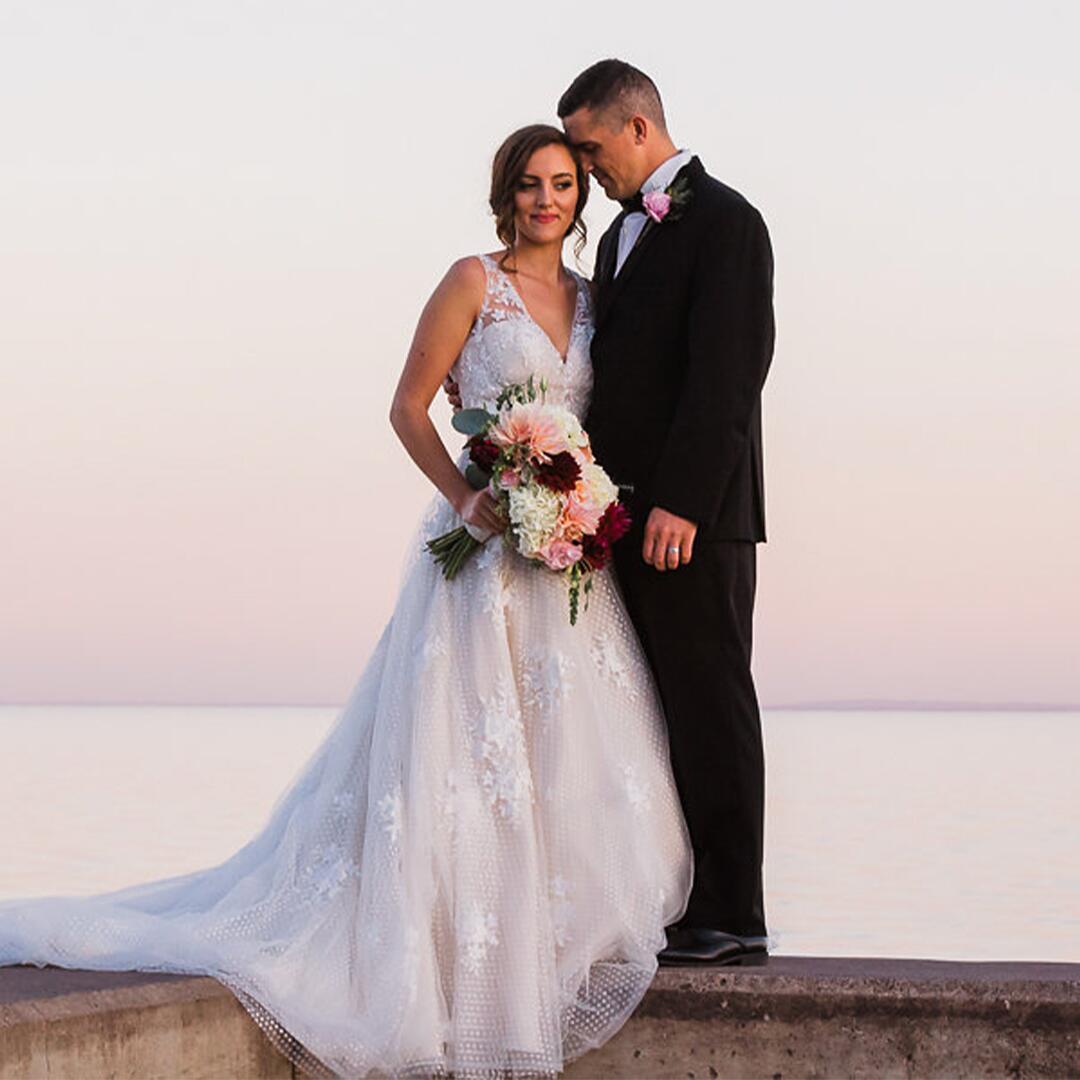 bride and groom standing on the pier, lake in the background
