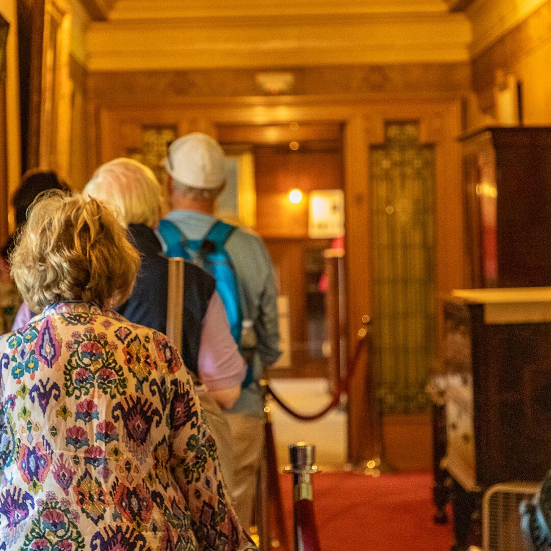three mature adults walking through a hall.