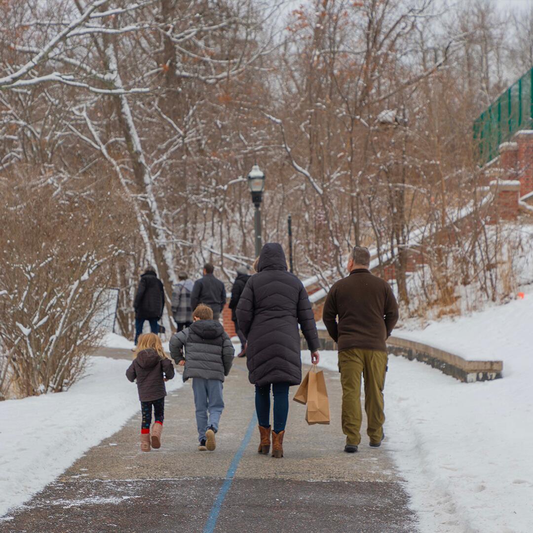 family walking up paved path to the front of the mansion.