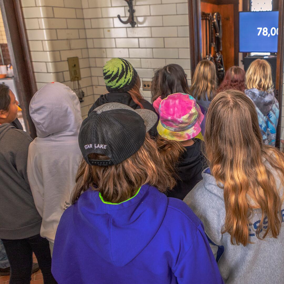 group of kids looking at an informations screen in the carriage house.