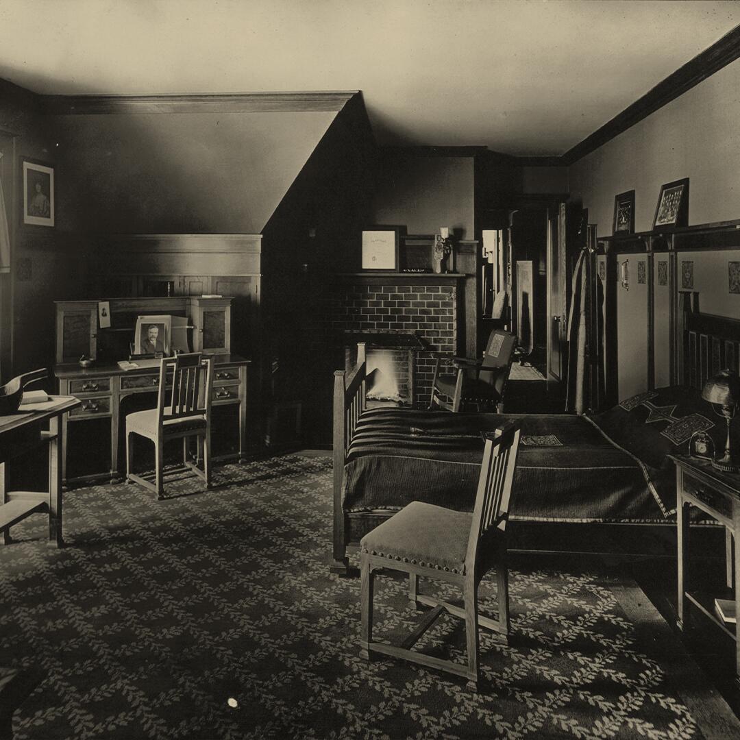 wood chair near twin bed, desk in corner, and fireplace in middle far wall of boys bedroom