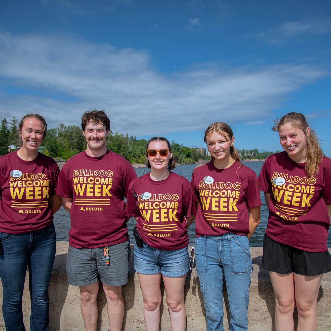 one adult and five students in matching shirts standing on the pier.