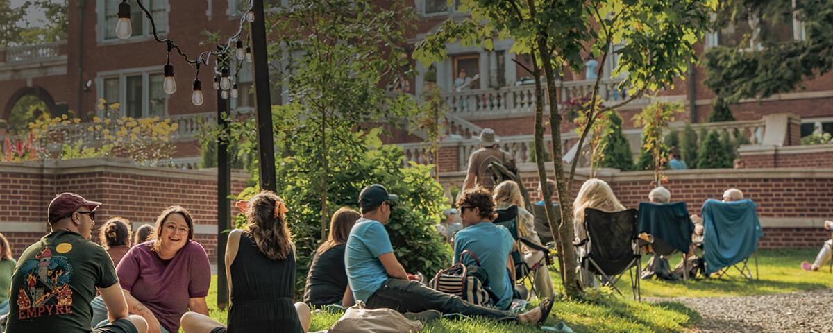 groups of guests sitting along the grass and paved path leading to Glensheen.