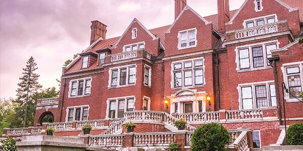 back side of orange brick exterior of Glensheen with colorful sunset.