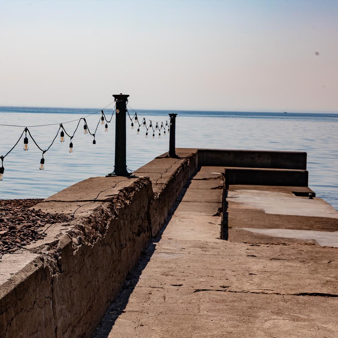 string lights hanging on a concrete pier in the lake.