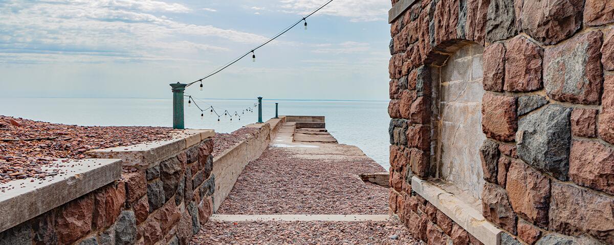 long concrete pier overlooking Lake Superior, stone boathouse to the right.