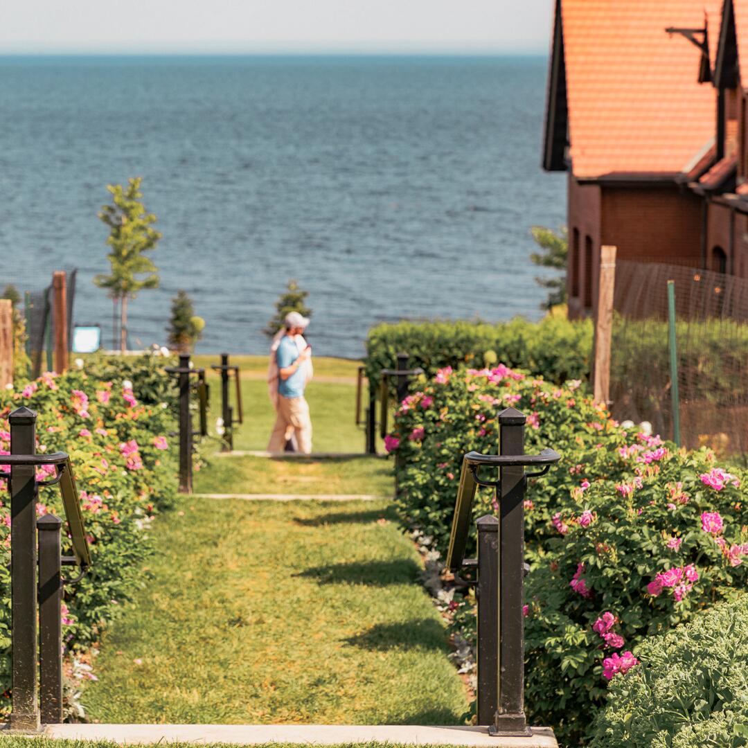 two guests walking past grassy tiered steps of a garden.