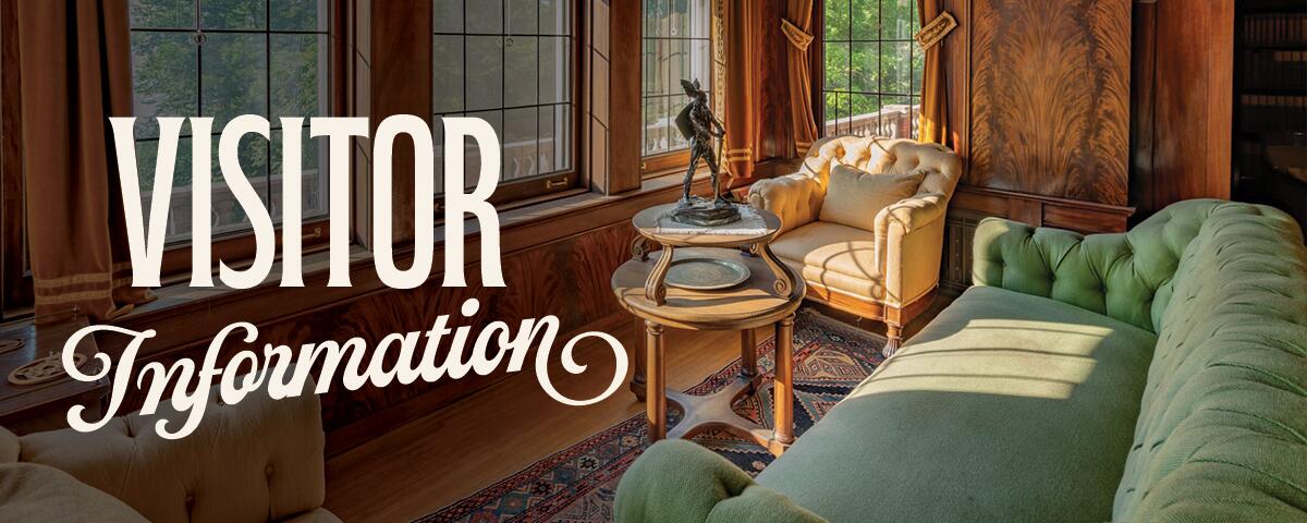 green tufted sofa and chair with round table and windows: Visitor Information