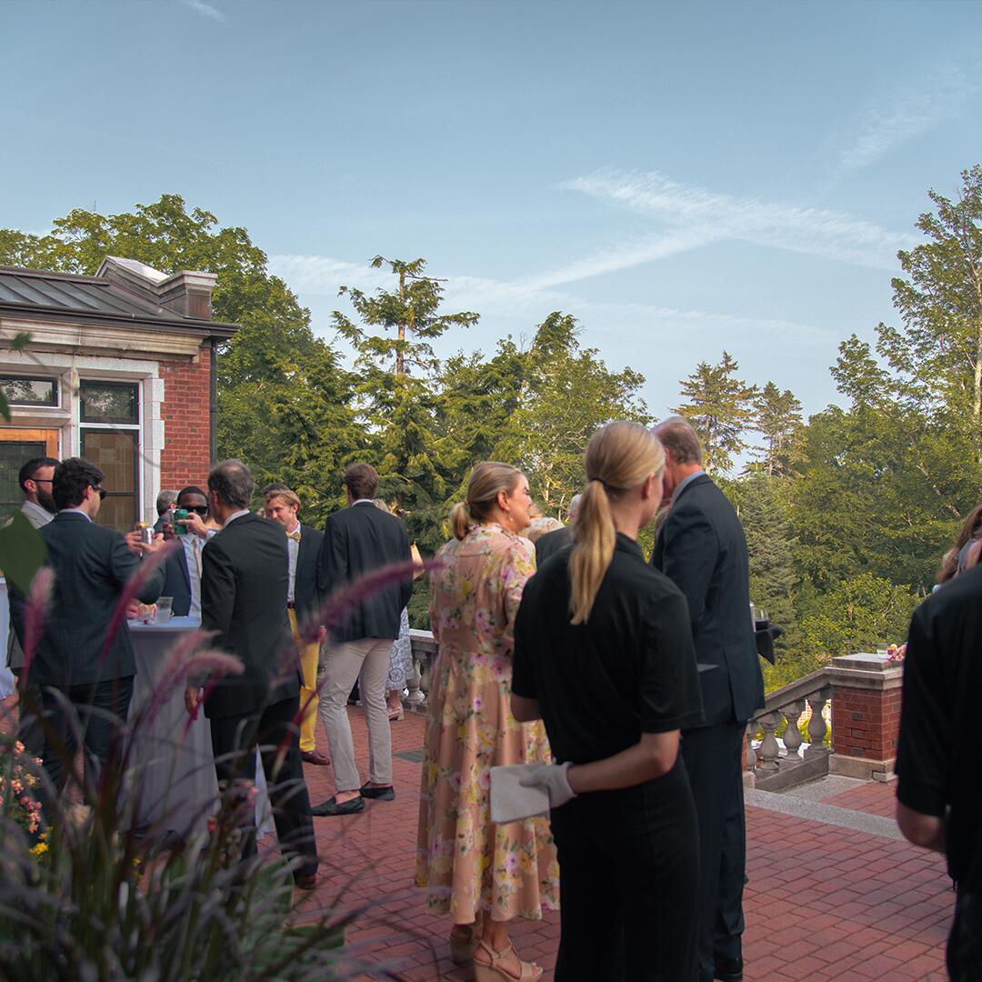Guests standing out on the brick terrace of Glensheen, chatting.