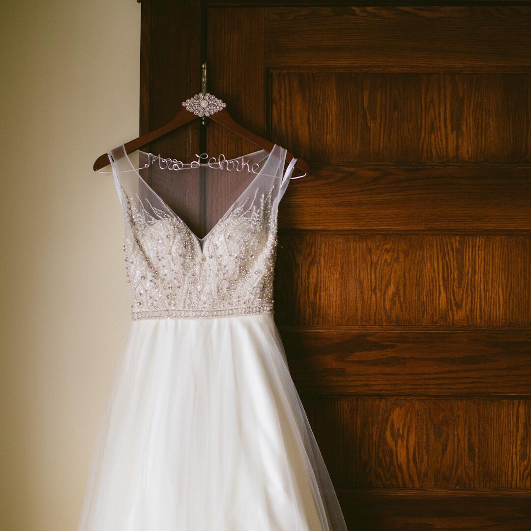 White wedding dress hanging on a wooden door of the Bridal Suite.