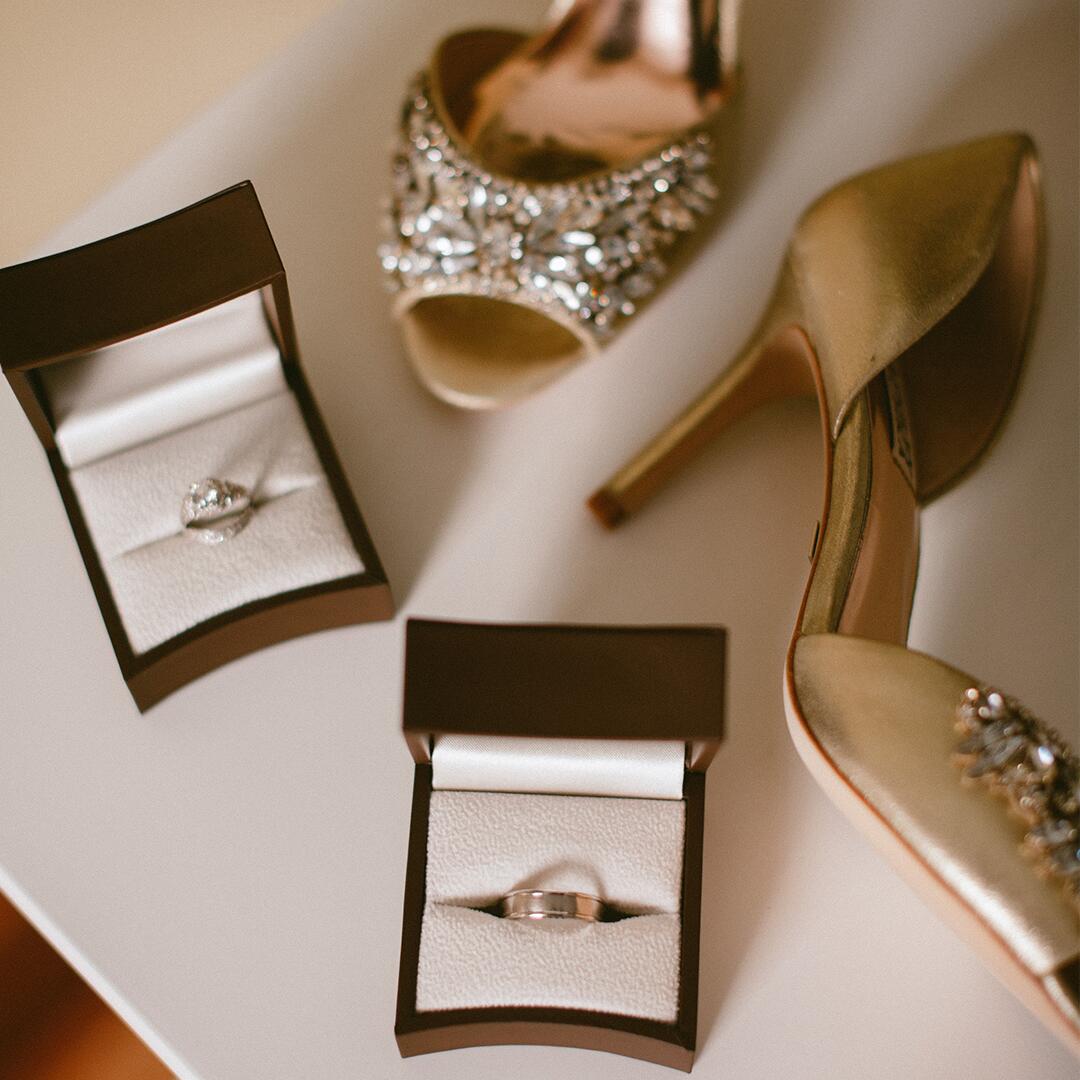 wedding rings in boxes on a table with high heels.