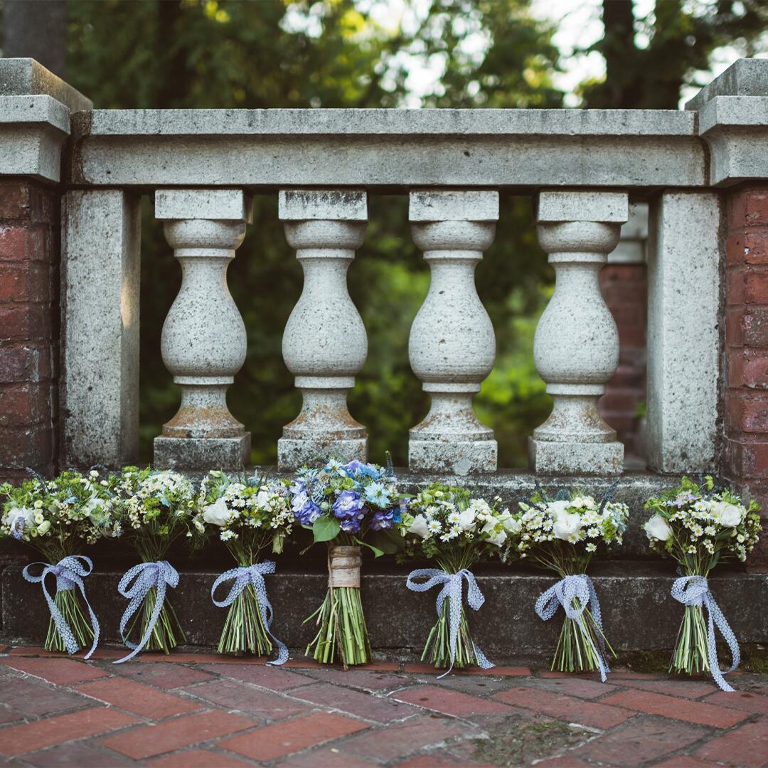 Seven flower bouquets resting on brick and stone terrace by Sternberg Studio Photography.
