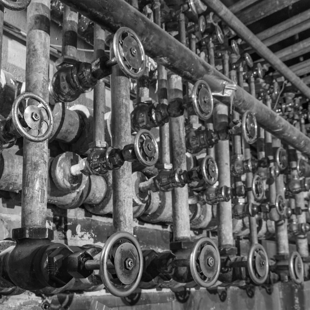 metal turn wheels and pipes on a wall in the boiler room
