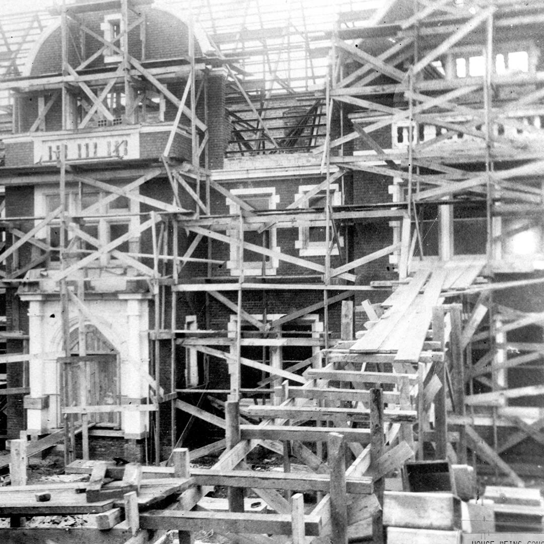 scaffolding and wood boards around a brick mansion under construction