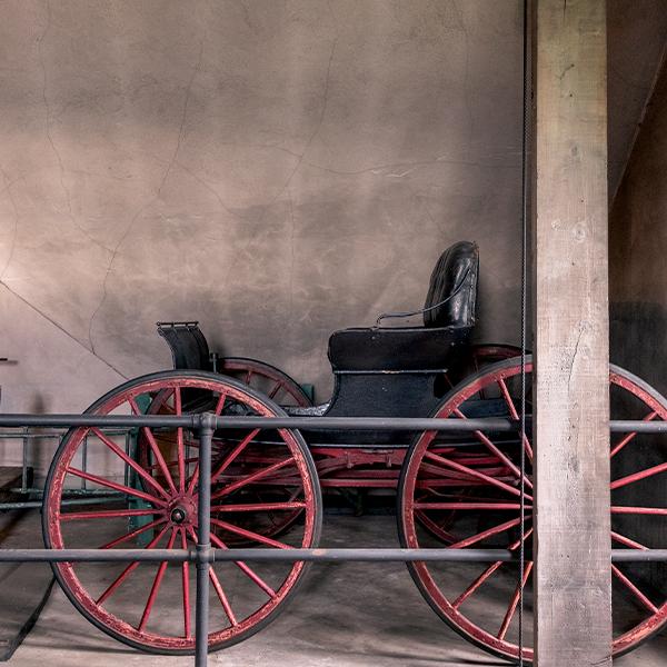 Black carriage with red wood wheels stored in upstairs of the Carriage House.