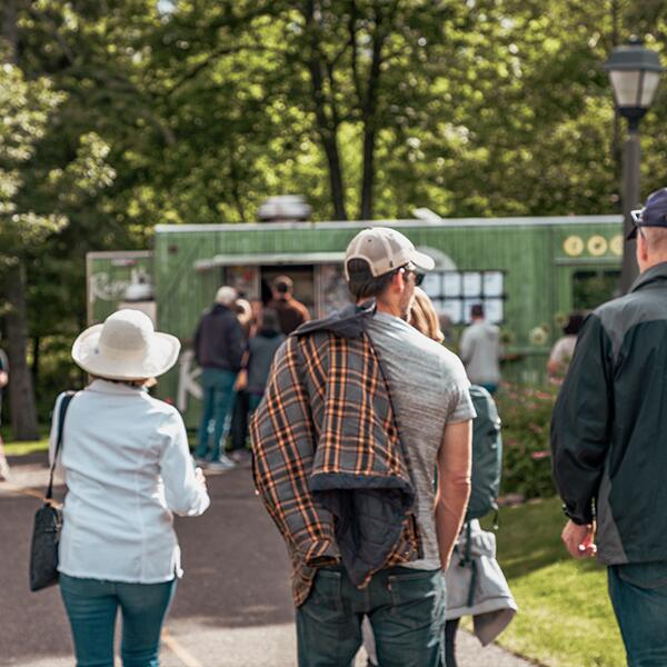 adults walking on paved path to green food truck
