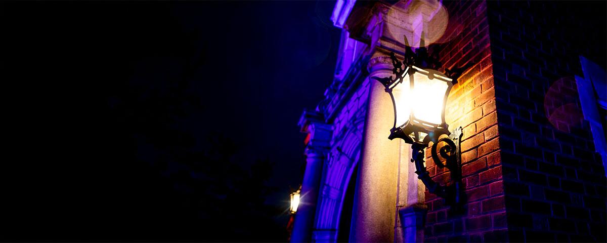 dark lit front door of mansion with lit lantern