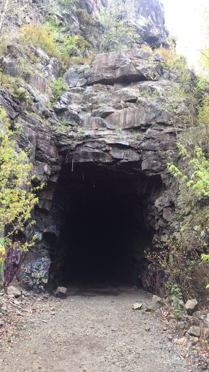 The old railroad tunnel inside of a large rock face.