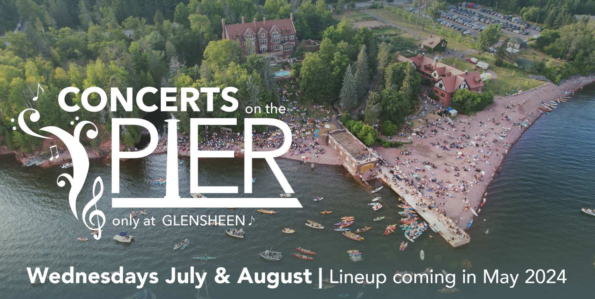 Concerts on the Pier, Wednesdays in July and August. Lineup coming May 2024. Image of a shoreline filled with boats on the water and people along a rock beach facing a concrete pier.
